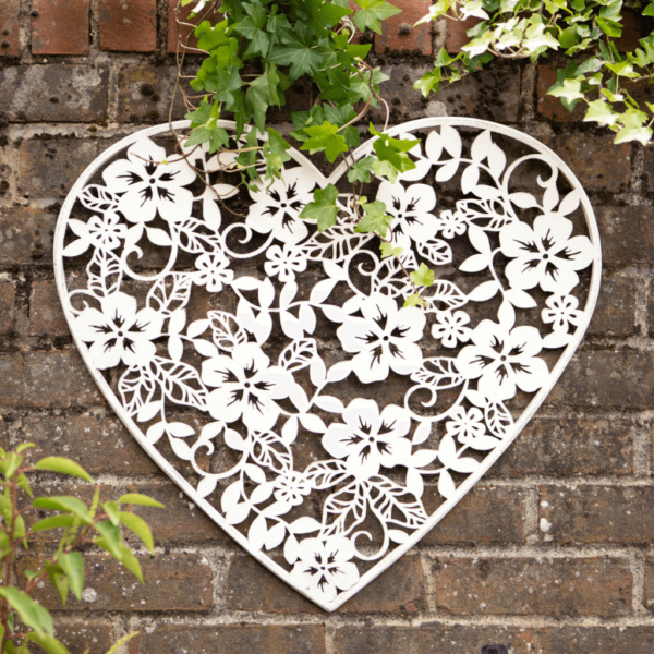 Heat shaped white metal wall plaque. heart shape with delicate flower cut out detail.