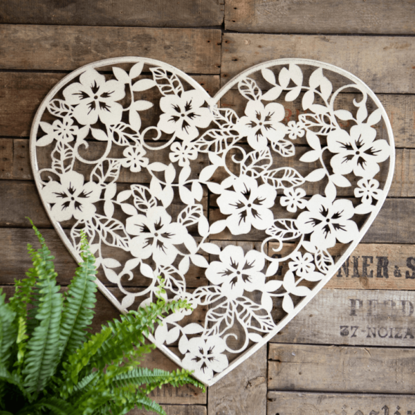 Heat shaped white metal wall plaque. heart shape with delicate flower cut out detail.